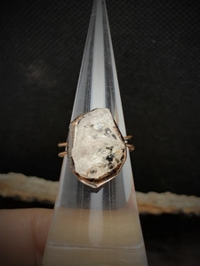 Detailed macro view of an unpolished natural crystal set in a dark wire adjustable ring