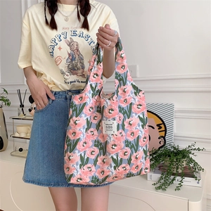 Dettaglio della borsa shopper in tela con fiori rosa su sfondo blu chiaro