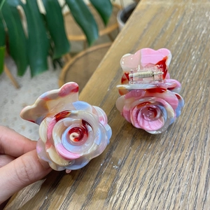 Close-up of acetate rose hair claws with marble texture on wooden table