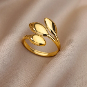 Detailed close-up of 18k gold-plated three-leaf ring on champagne satin fabric