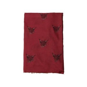 Close-up of burgundy scarf featuring black highland cow print and delicate fringed edges