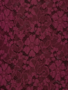 Close-up detail of wine red lace fabric with intricate floral hollow patterns on the dress