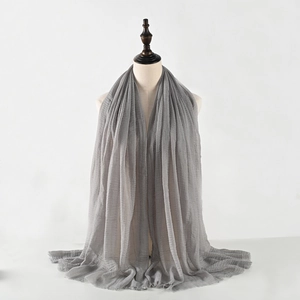 Detail showing the gray crinkled cotton-linen scarf with fringed edges on a model
