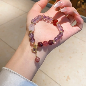 Detailed close-up of beaded crystal bracelet with amethyst, quartz and golden pendant