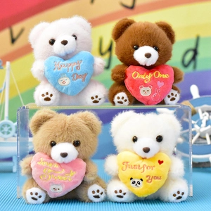 Detailed view of colorful plush teddy bear keychains holding hearts with sweet messages