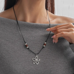 Détail du pendentif fleur argentée sur cordon ciré noir avec perles marron rouge