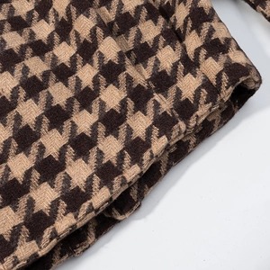 Detailed close-up of thick houndstooth plaid fabric texture on a two-piece fashion set