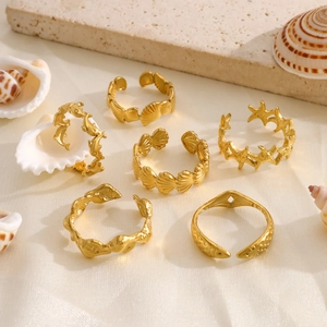 Flat lay of gold starfish and seashell rings set on silk with natural stone props