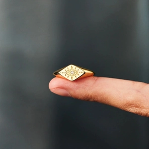 Detailed view of a gold-plated signet ring featuring a diamond-shaped evil eye motif