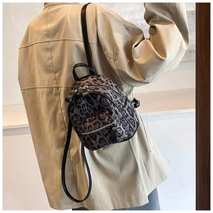 Detalle de una mini mochila con estampado de leopardo llevada por modelo en beige