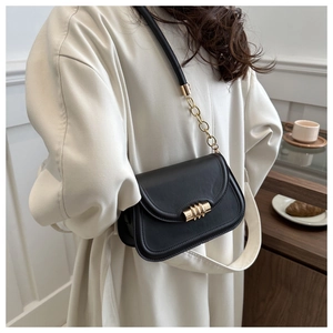 Detail of elegant black leather shoulder bag with gold hardware shown in a cafe setting