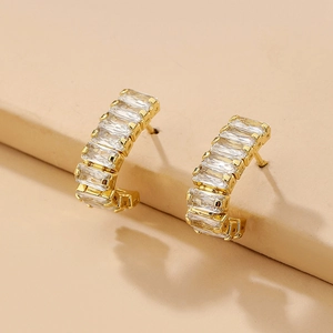 Detail of C-shaped gold-plated hoop earrings featuring channel-set baguette cubic zirconia