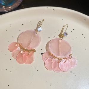 Close-up of pink shell resin pendant earrings with gold hooks and white zircon accents