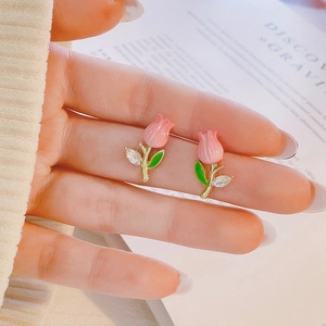 Detail of tulip stud earrings with pink petals and gold stems featuring clear zircon leaves