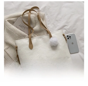 Detail view of large white leather tote bag compared with a smartphone for size reference