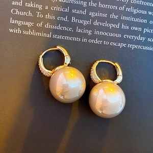 Macro shot of gold hoop earrings with zircon accents and elegant hanging pearl