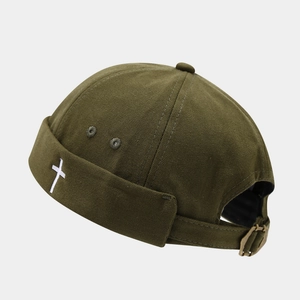 Detail view of military green brimless cap with white cross embroidery and metal strap buckle