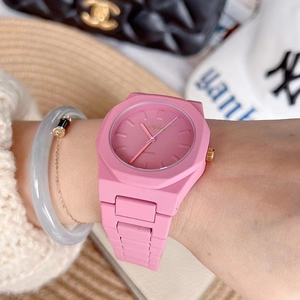 Close-up of a pink octagonal lady's watch with silicone strap on wrist with lifestyle props
