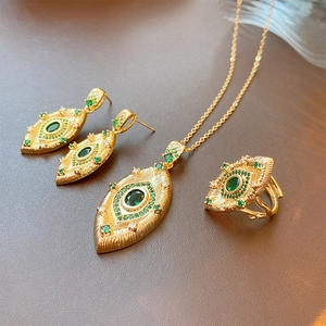 Macro shot of vintage gold jewelry set with green stones and sparkling zirconias