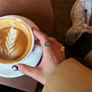Silver flower ring set worn by hand near a coffee cup on a warm wooden table