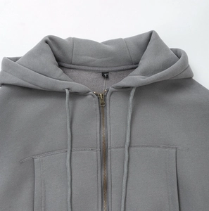Close-up of metal zipper and stitched collar detail on a grey hooded tracksuit
