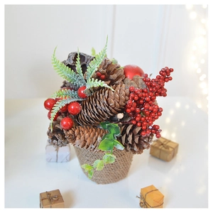 Christmas pine cone and berry miniature plant in burlap pot on a festive table