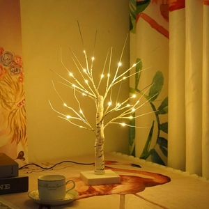 Illuminated white birch LED tree with warm lights on a cozy desktop setting