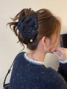 Detail of dark blue tweed bow hair claw with gold sequins worn on elegant hairstyle