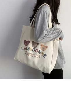 Side view of a large cream canvas tote bag with cartoon bear prints on a model shoulder
