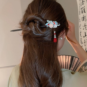 Detail of Chinese tassel hair pin with blue enamel flowers and red drop bead on hair bun