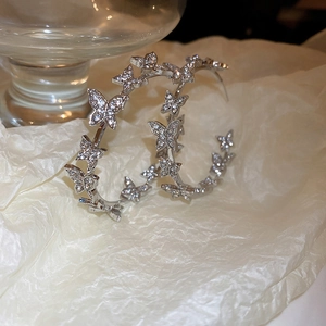 Detail of silver hoop earrings featuring rhinestone-studded butterfly links