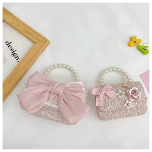 Detail of pink tweed girl bags with elegant pearl handles and silk bow decorations