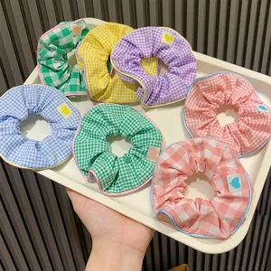 Set of colorful gingham scrunchies in candy colors with cute heart labels in a tray