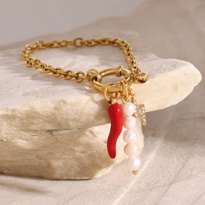 Détail d'un bracelet en or 18k avec piment rouge, perles et breloques éclair sur pierre