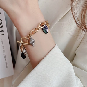 Detail of gold chain bracelet with sea shell charm and T-bar toggle closure