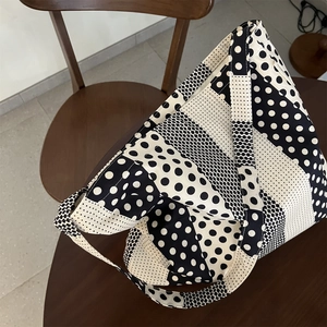 Vista dettagliata di una borsa tote in tela a pois bianchi e neri su tavolo in legno