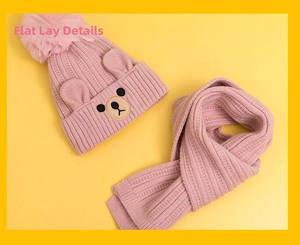 Detailed flat lay of pink knitted bear beanie with faux fur pompom and matching scarf