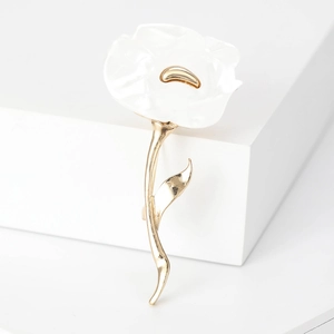 Detail showing the white enamel flower petals and gold metal stem of the floral brooch