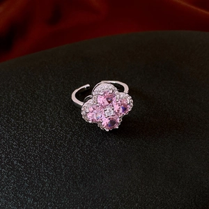 Macro detail of silver four-leaf clover ring with pink heart-shaped stones and tiny diamonds