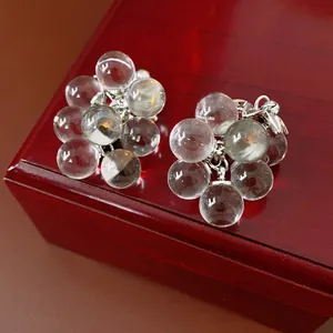 Silver needle crystal grape cluster earrings with transparent beads on a red wood box