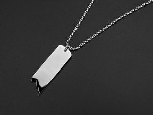 Détail du collier chaîne argenté avec pendentif règle brisée sur fond noir texturé