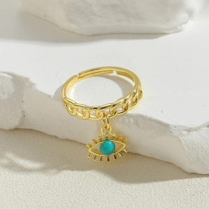 Bohemian gold evil eye charm ring with cuban chain design on a white stone pedestal