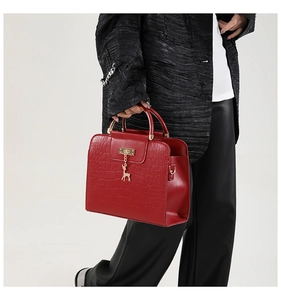 Detail of red faux crocodile leather handbag with golden handle and deer charm