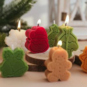 Christmas scented candles set with tree, ginger man and bell in a warm festive setting