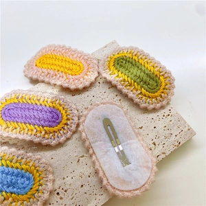 Macro detail of colorful hand-knitted hair clips with metal BB clips on stone surface