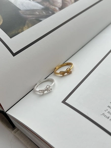 Macro detail of S925 sterling silver bow ring with crystals on minimalist magazine