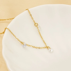 Elegant gold chain bracelet with zircon charms displayed on a white ceramic plate