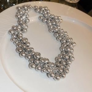 Detailed view of multilayer silver beaded choker with metallic luster on white tray