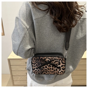 Detail of leopard print crossbody bag with black bow and stylish wide shoulder strap