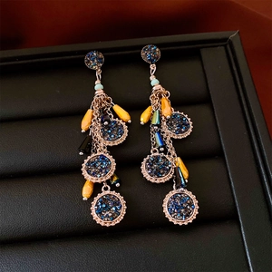 Détail de boucles d'oreilles bohèmes avec pampilles étoiles bleues et perles jaunes